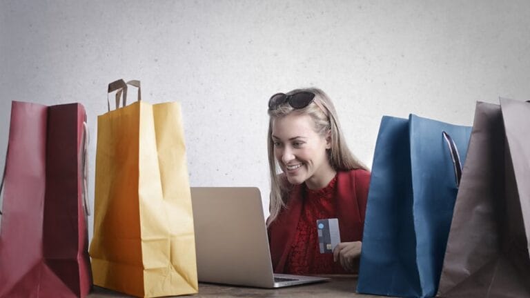 Woman shopping online with a credit card and holiday shopping bags.